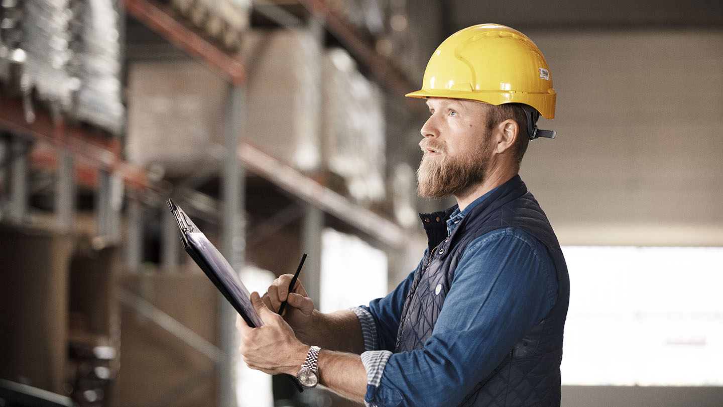Man with yellow hat checking of a list.
